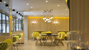 A modern dining area with yellow chairs, a round table, and a bowl of lemons. - Citadines Ramblas Barcelona (Barcelona)