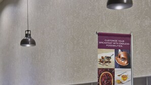A breakfast bar with various food items and condiments, a refrigerator, and a sign promoting customizable breakfast options. - Residence Inn Milwaukee Downtown by Marriott (Milwaukee)
