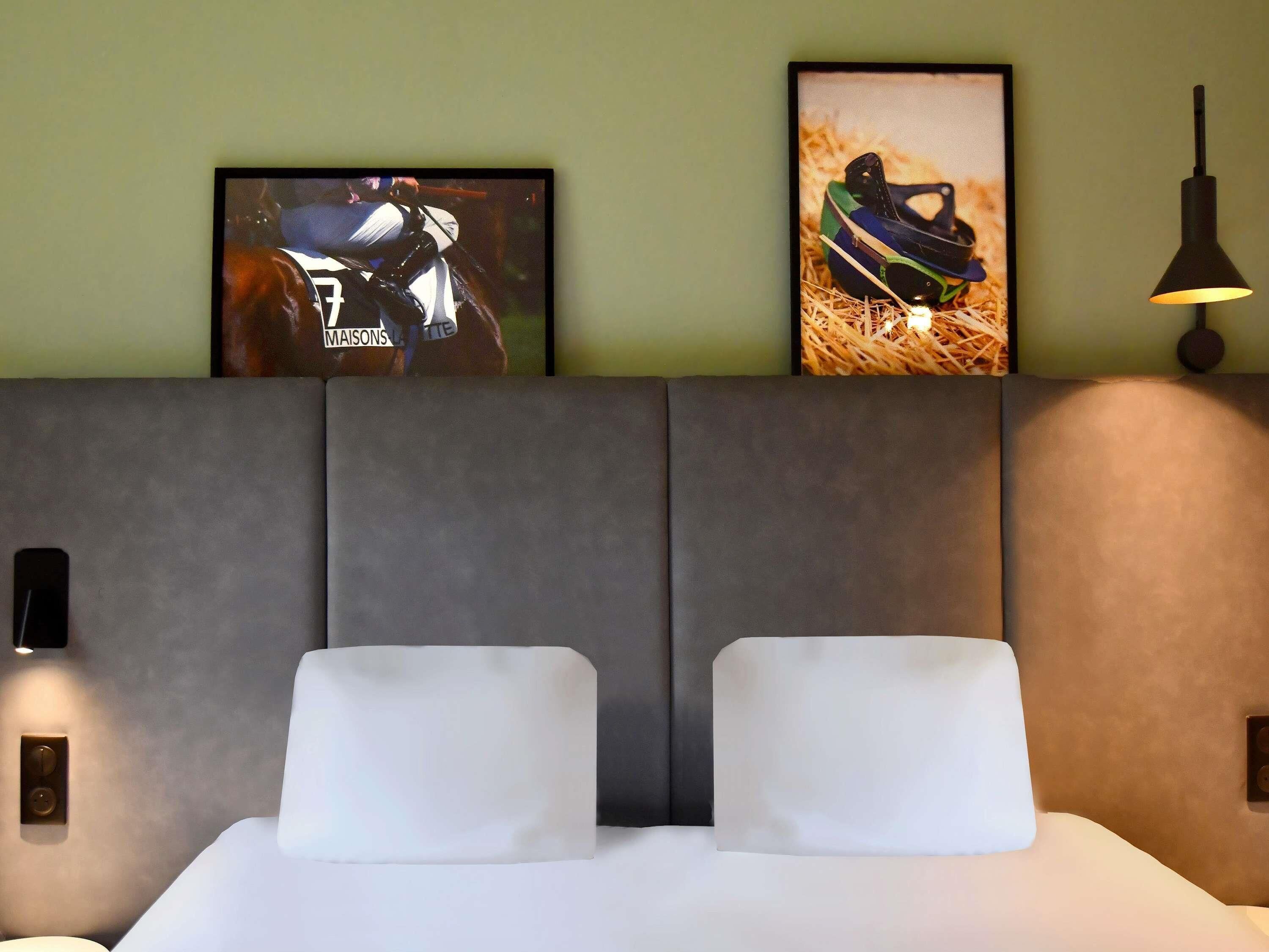 Une chambre d’hôtel avec un grand lit, deux oreillers, une tête de lit et deux appliques murales.