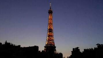The Eiffel Tower at dusk with its lights illuminated against a dark sky.