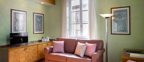 A living room with a sofa, a coffee table, a television, and artwork on the walls.