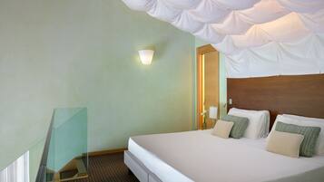 A hotel room with a large bed, a bedside table, a wall-mounted light, and a mirror.