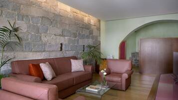 A living room with a stone wall, a brown leather sofa, a glass coffee table, and a wooden cabinet.