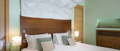 Una habitación de hotel con una cama grande, dos mesitas de noche, una lámpara, un florero con flores y un cabecero de madera.