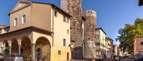 A street with historic buildings, including a tower and a building with arches.