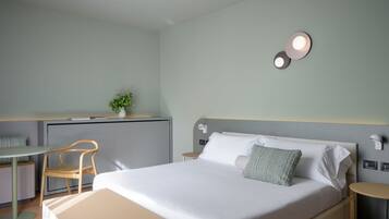Una habitación de hotel moderna con cama, escritorio, silla y una mesita.