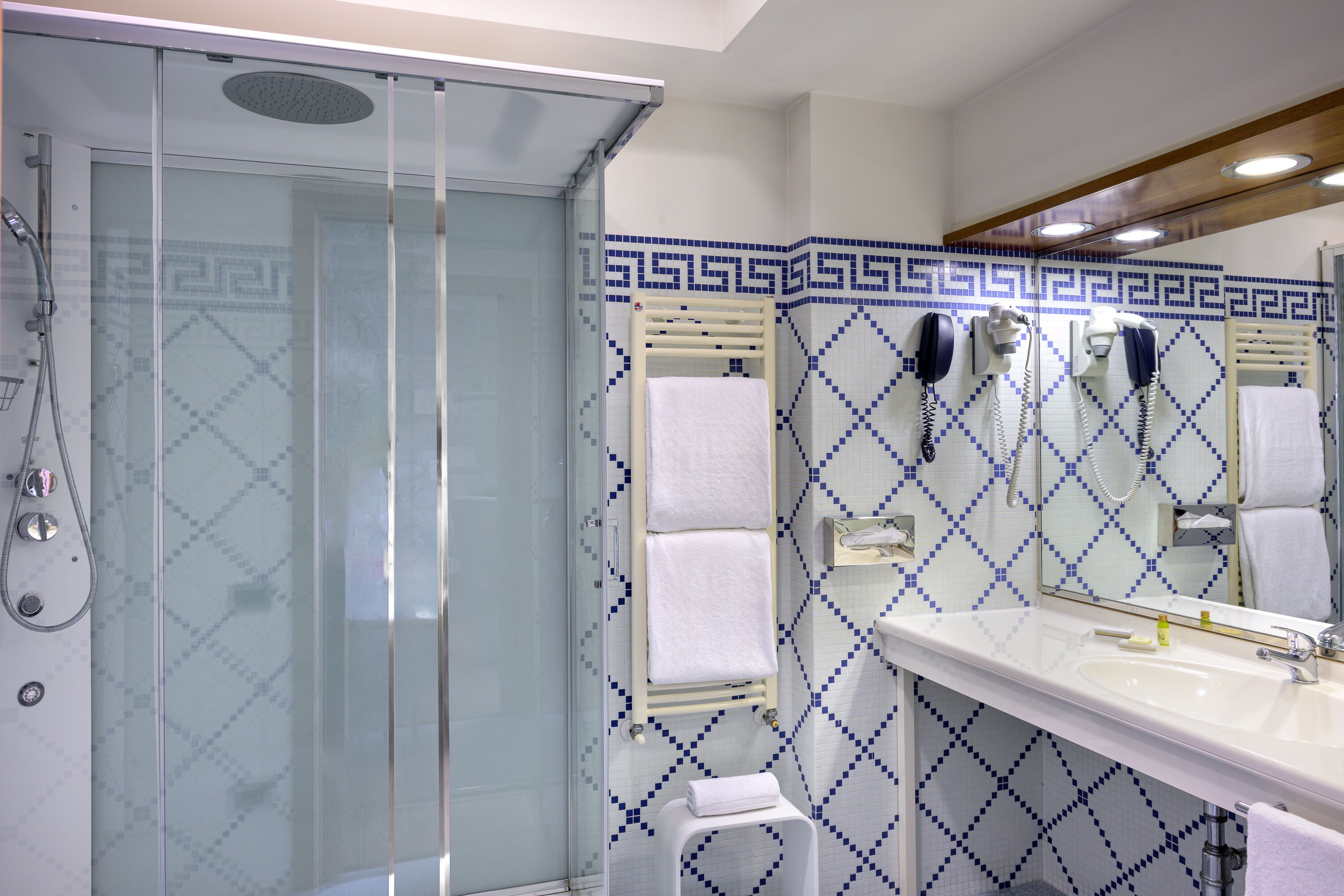 A bathroom with a glass-enclosed shower, a white sink, and a mirror above it.