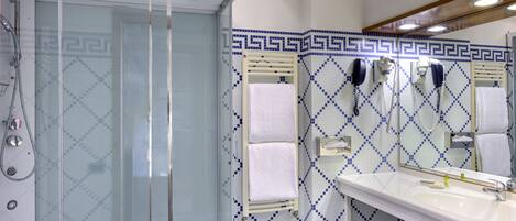 A bathroom with a glass-enclosed shower, a white sink, and a mirror above it.