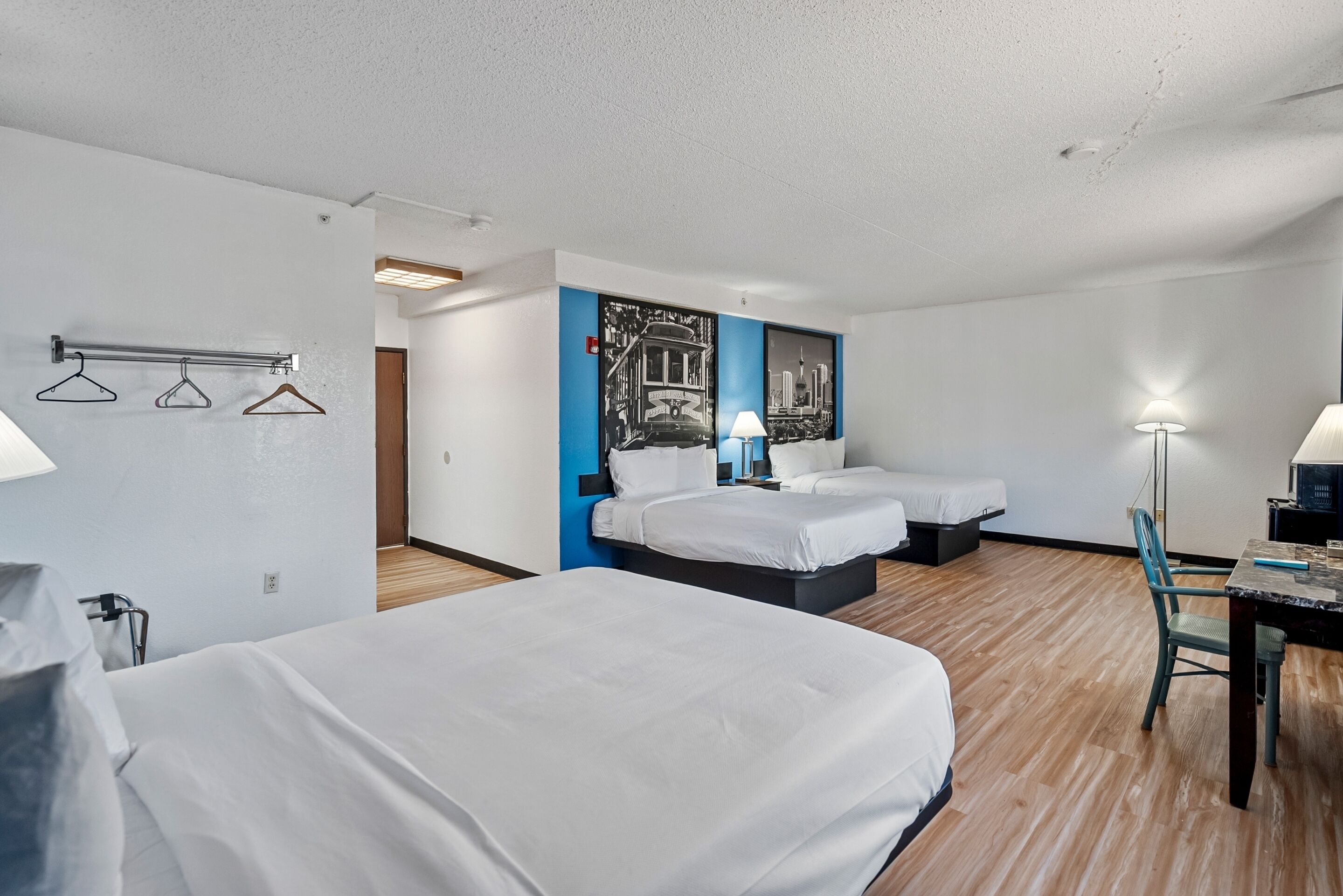 A hotel room with two beds, a desk, and a chair.