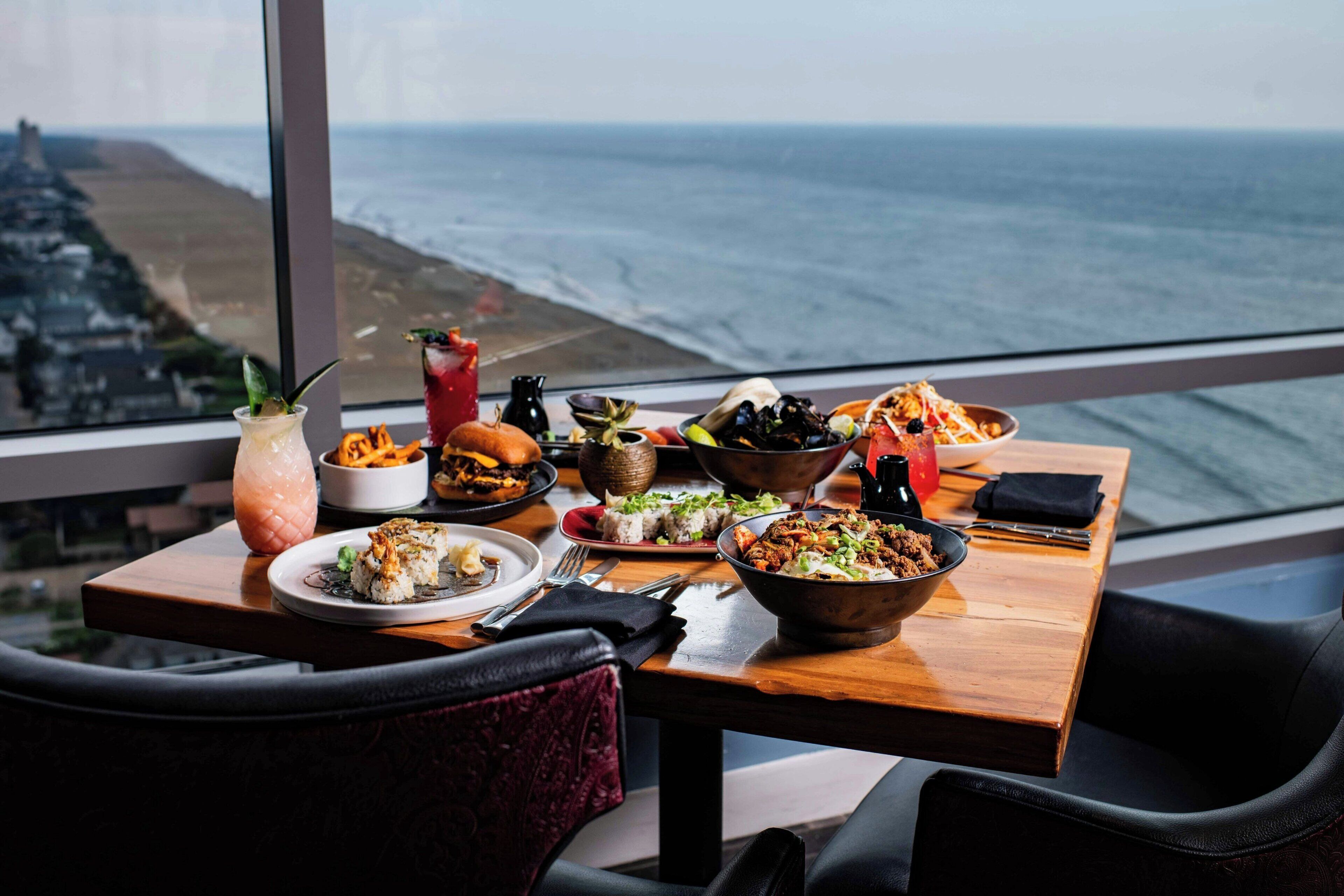 A dining table with various dishes and a view of the ocean.