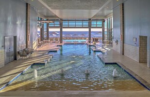 Una piscina techada, una piscina al aire libre, sombrillas