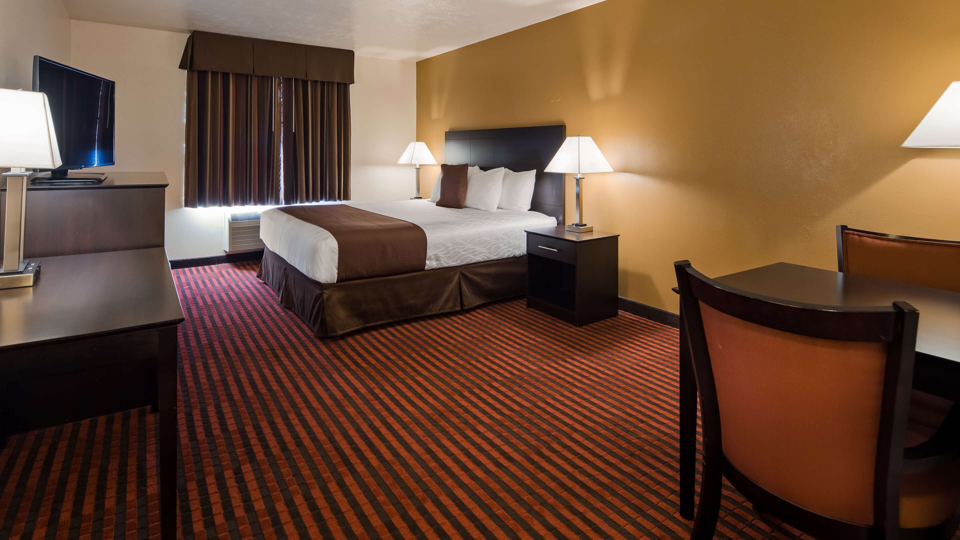 Une chambre d’hôtel avec un lit, des tables de chevet, un bureau et une chaise.