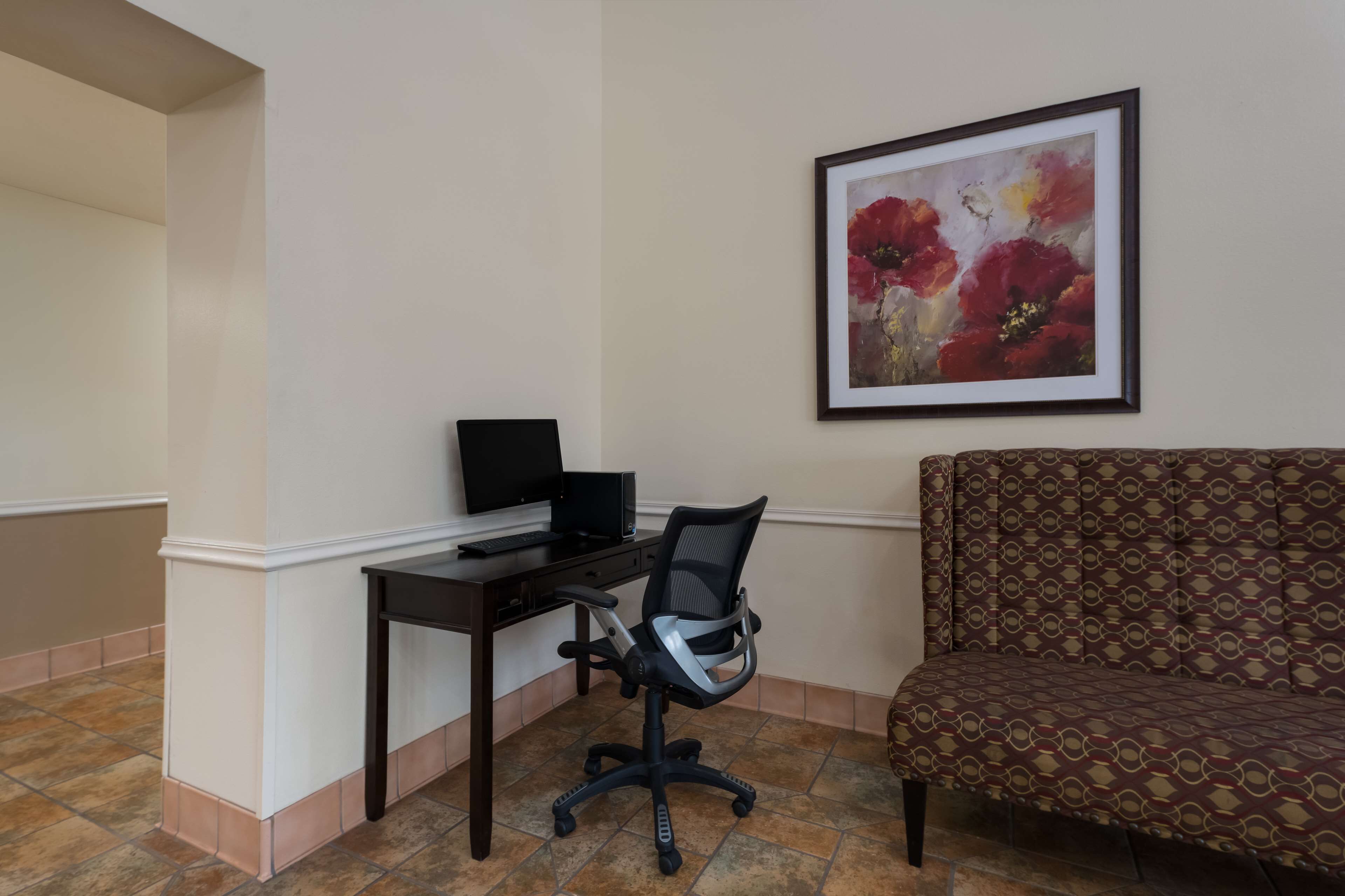 A room with a desk, office chair, and a sofa.