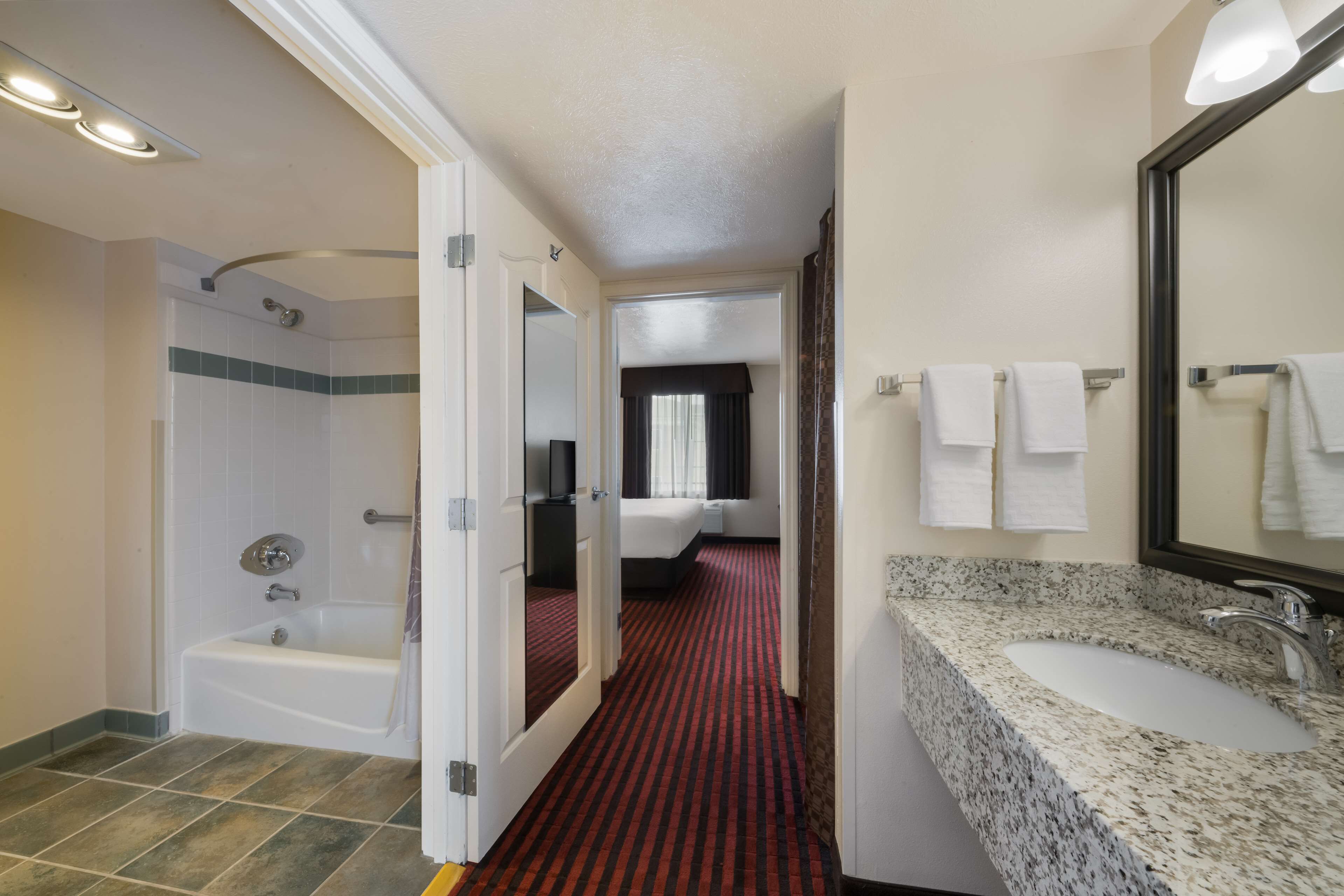Un baño de hotel con bañera, lavamanos y espejo.
