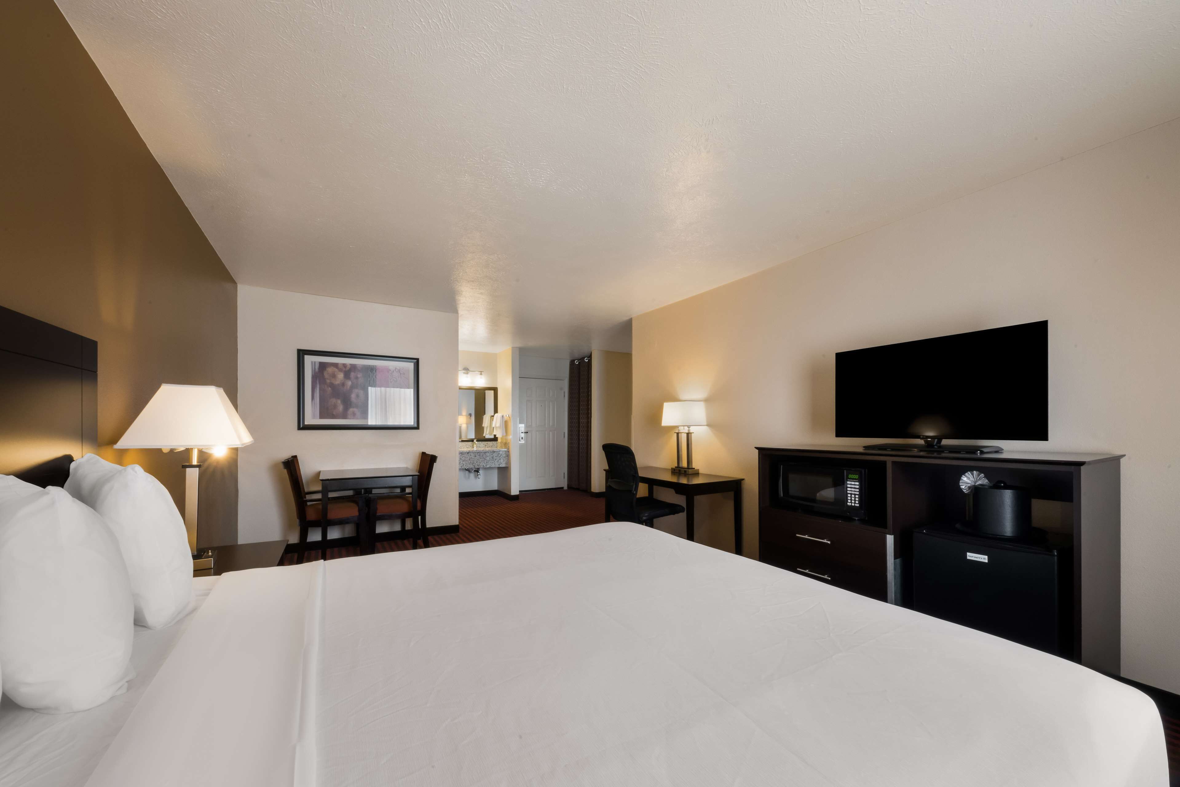 Una habitación de hotel con una cama grande, un escritorio con una silla, un televisor y un microondas.