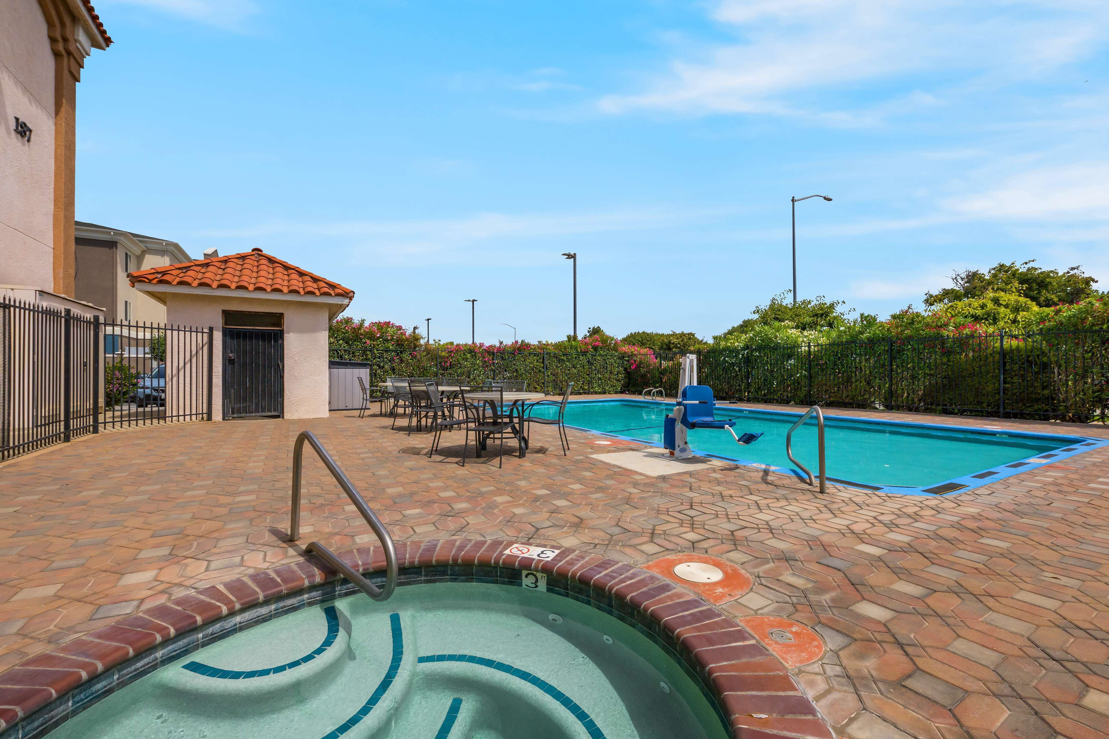 A swimming pool area with a tiled deck, a small pool, and a covered seating area.