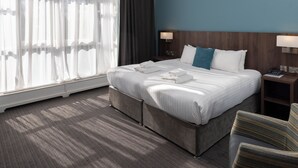 A hotel room with a large bed, two bedside tables with lamps, a window with sheer curtains, and a striped chair. - The Jephson Hotel, BW Signature Collection (Royal Leamington Spa)
