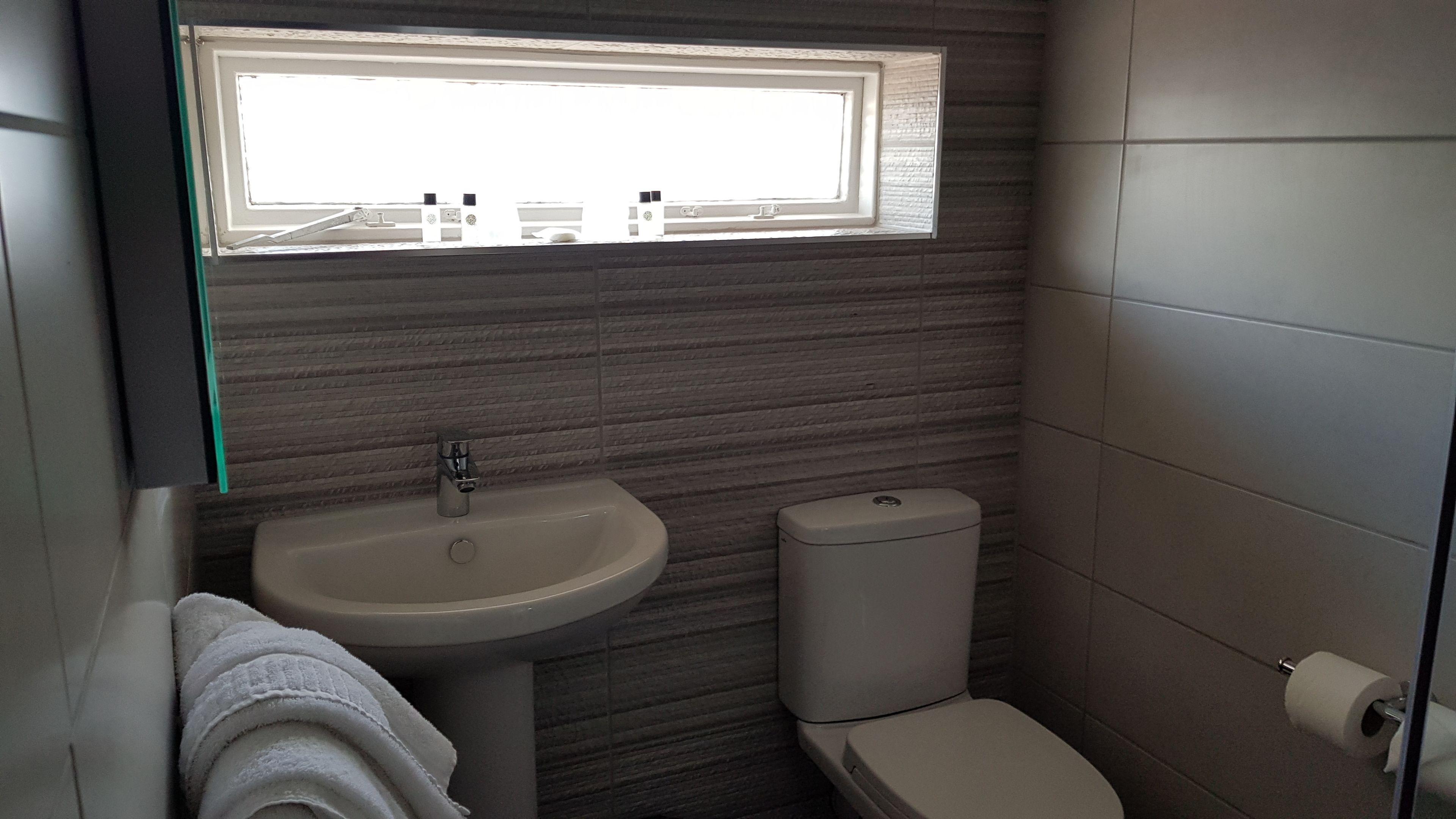 Un baño con ventana, lavamanos y retrete.