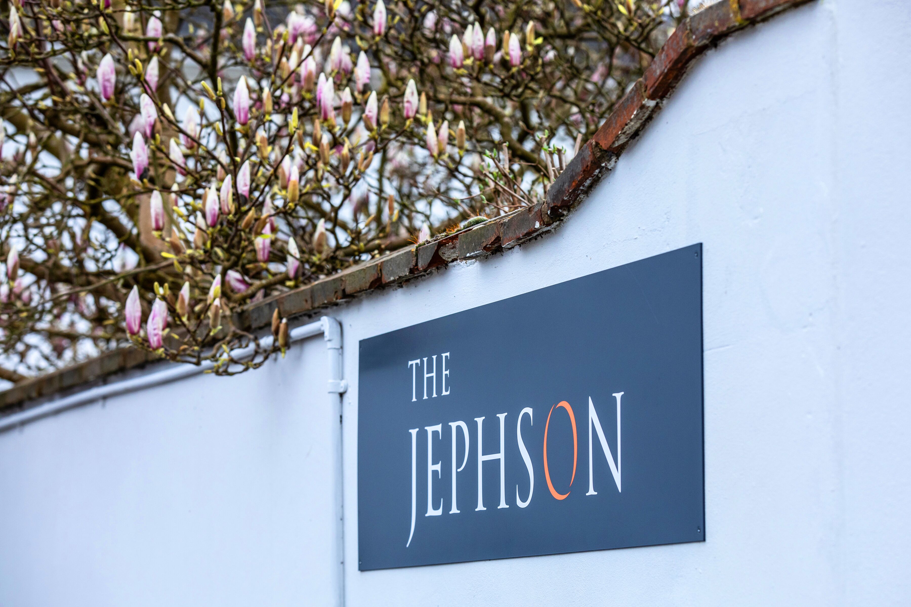 A sign with the text "THE JEPHSON" mounted on a white wall.