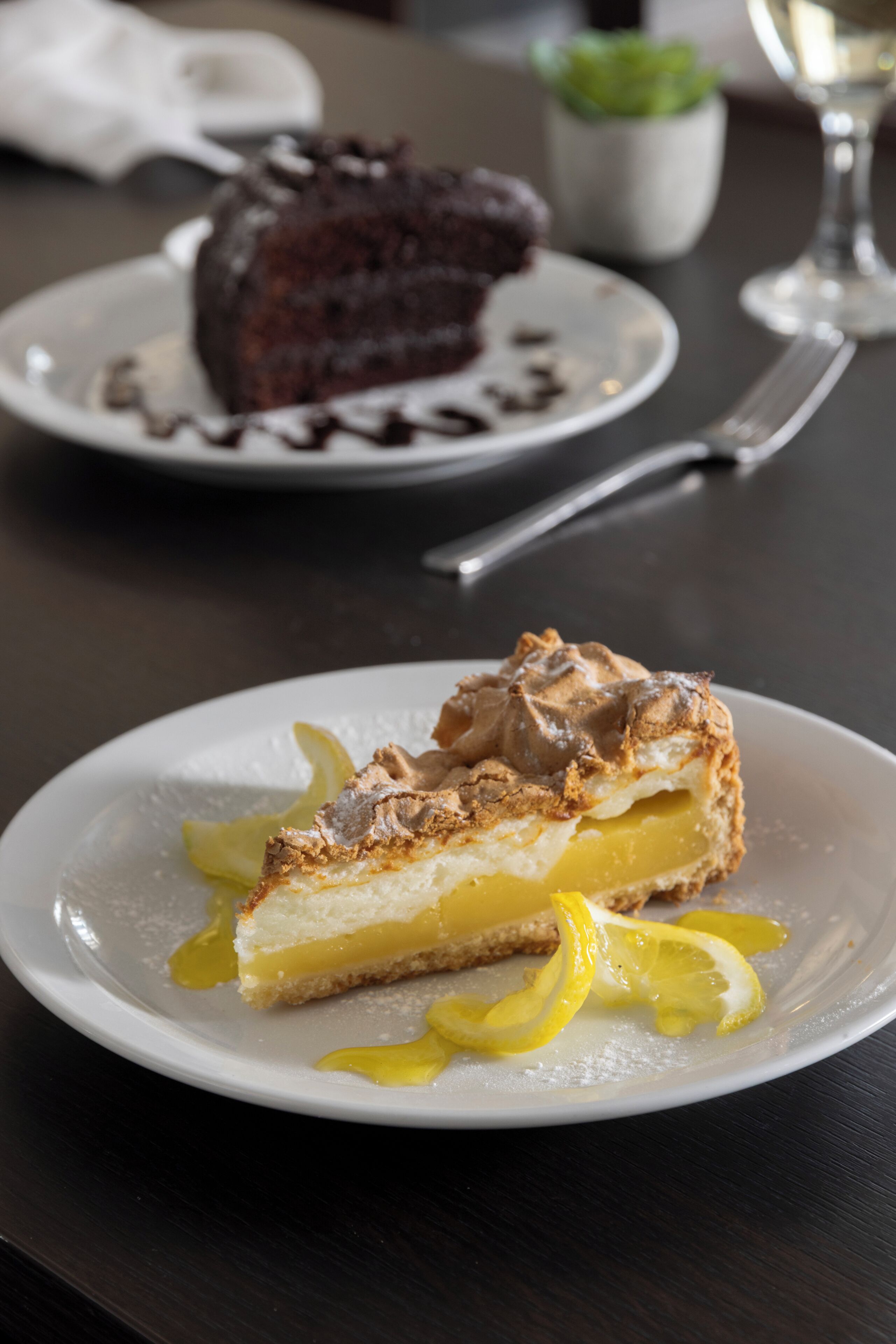 A dessert plate with a lemon tart and a chocolate cake on a table.