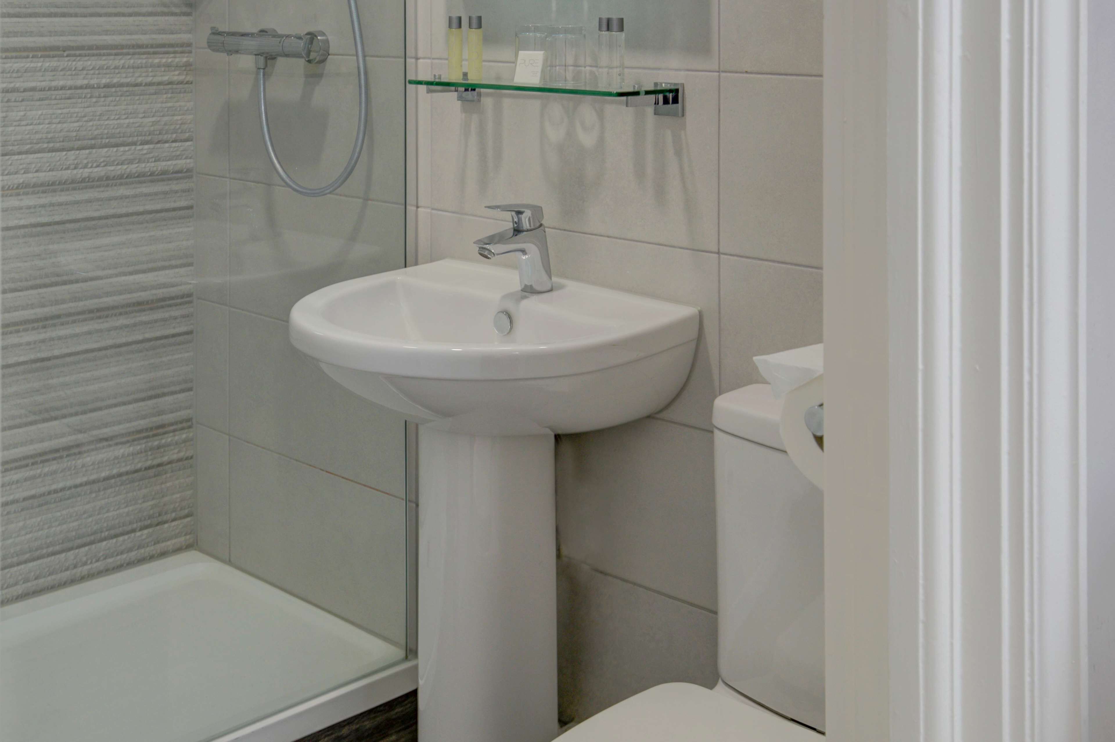 A bathroom with a white sink, a glass shower enclosure, and a toilet.