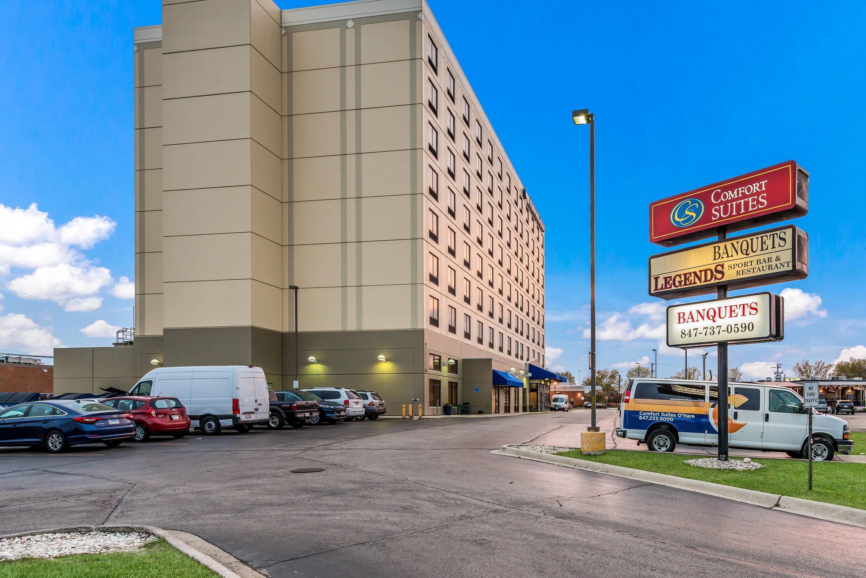 A hotel with a parking lot, a sign for Comfort Suites, and a Legends Sports Bar & Restaurant.