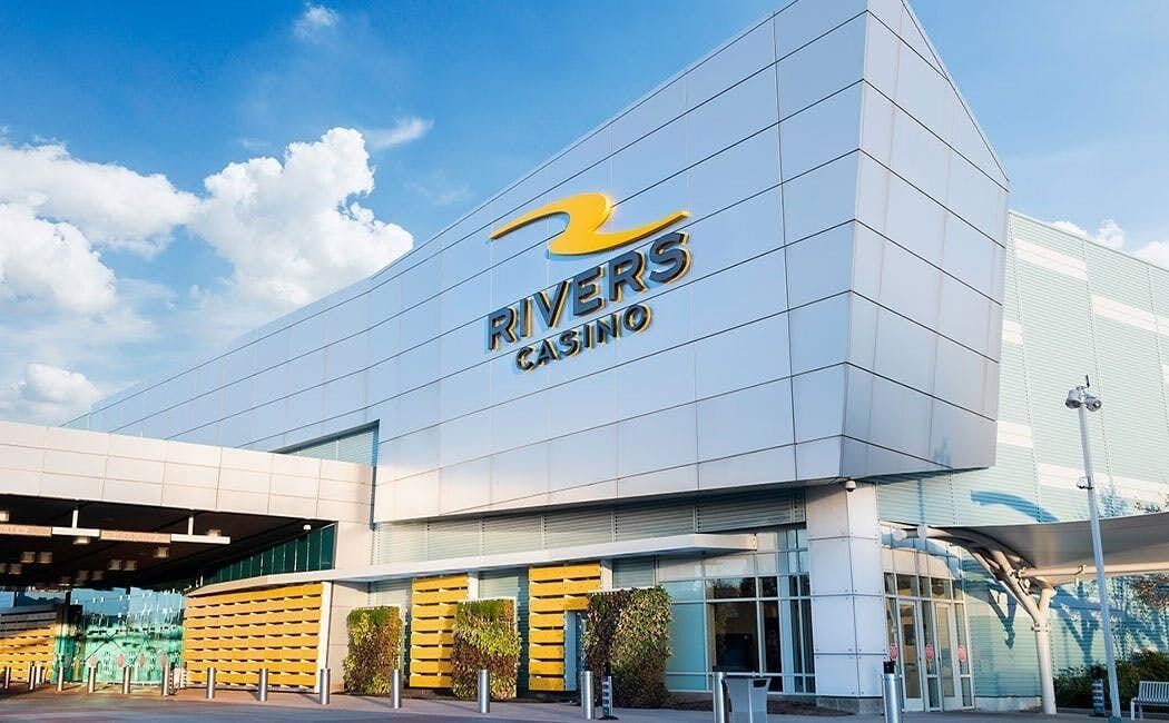 El edificio del Rivers Casino, con un diseño moderno, presenta un logotipo destacado y una entrada amplia.
