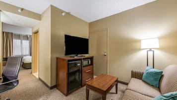 Una habitación de hotel con cama, escritorio, televisor, microondas y sofá.