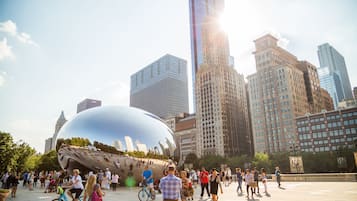 A public square with a large reflective sculpture surrounded by modern buildings and a crowd of people.