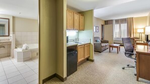 A hotel room with a kitchenette, a bathroom, a seating area, and a desk. - Comfort Suites Chicago O'Hare Airport (Schiller Park)