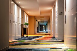 A hotel hallway with a colorful carpet, a potted plant, and a sign indicating room number 17. - United Hotel (Taipei)