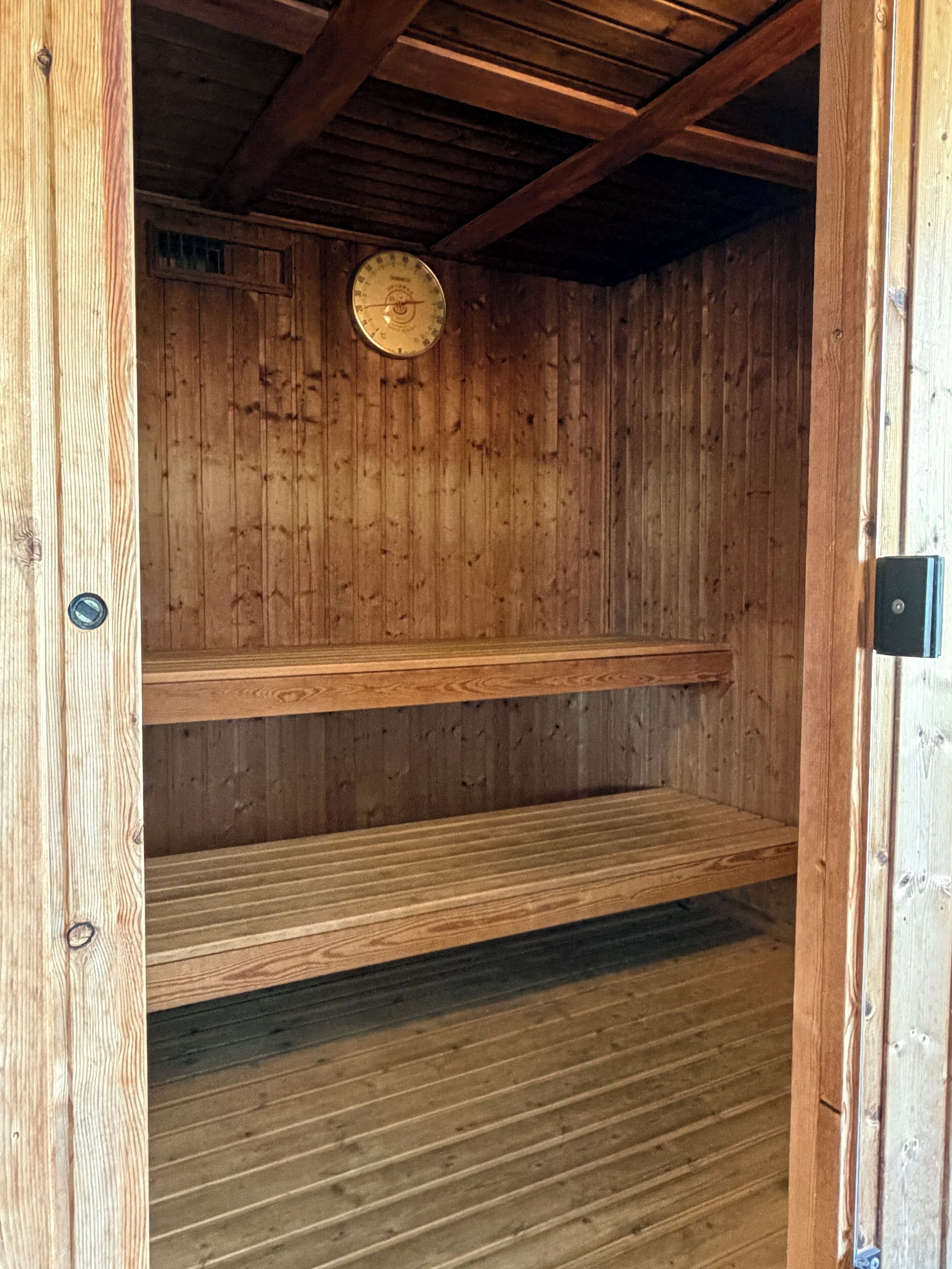 A wooden sauna with two benches and a wooden ceiling.