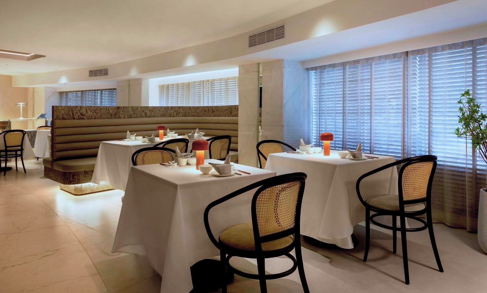 A dining area with round tables, chairs, and a cushioned bench.