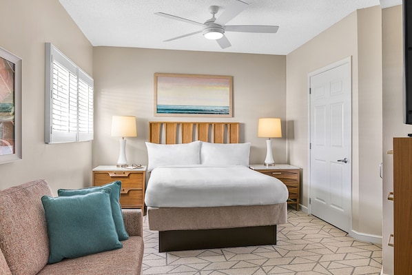 A hotel room with a bed, two bedside tables, a ceiling fan, a painting, and a patterned floor. - Marriott's Villas at Doral (Miami)