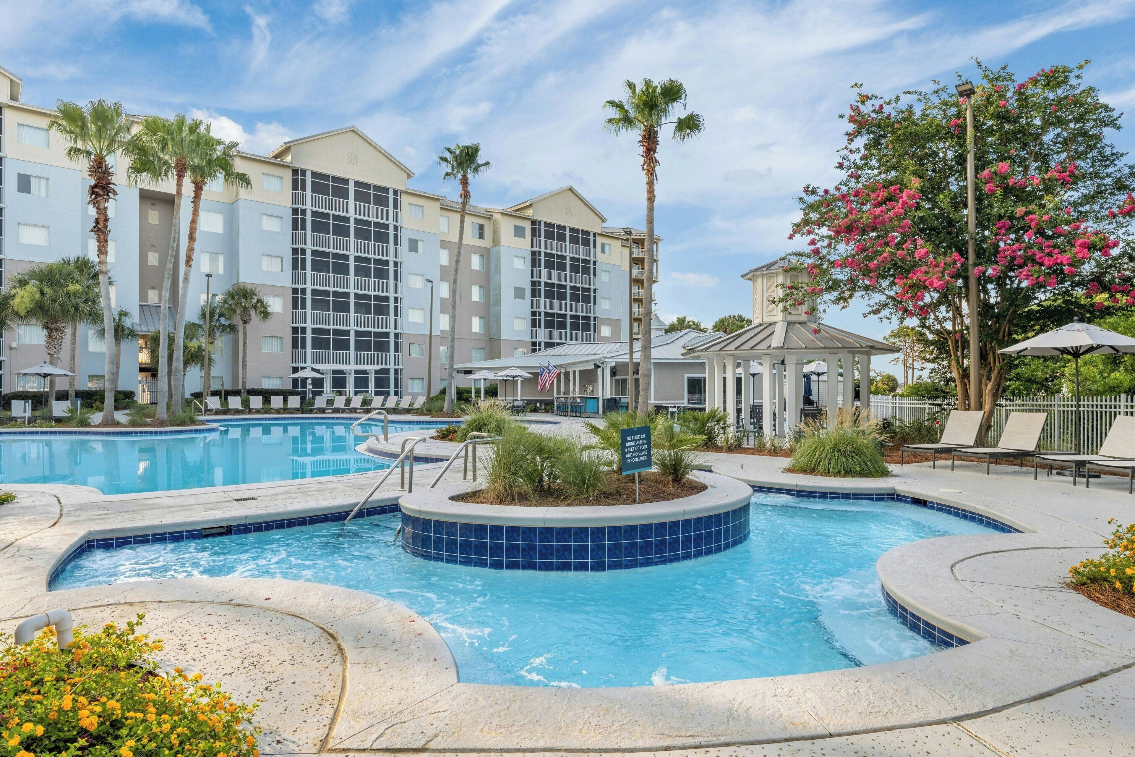 Un hotel con piscina, palmeras y un pabellón.