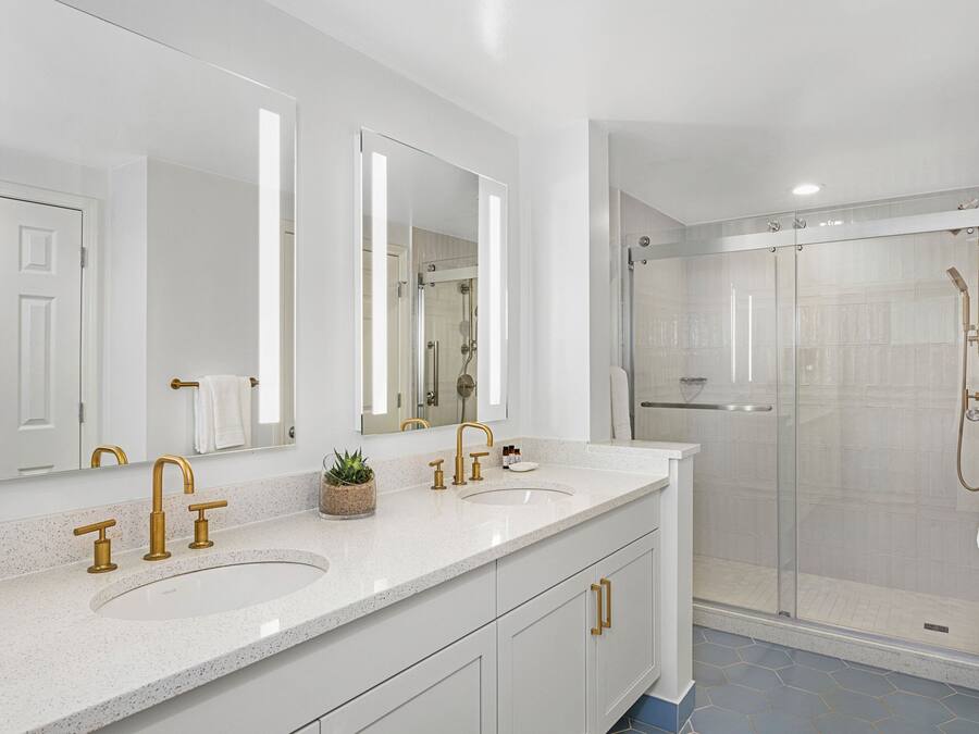 Un baño moderno con lavamanos doble, espejos grandes y ducha con cerramiento de vidrio.