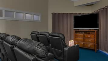 Una sala de cine en casa con butacas de cuero reclinables, un televisor de pantalla plana grande y un mueble de entretenimiento de madera.