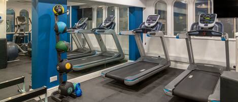 A gym with treadmills, weight machines, and exercise balls.