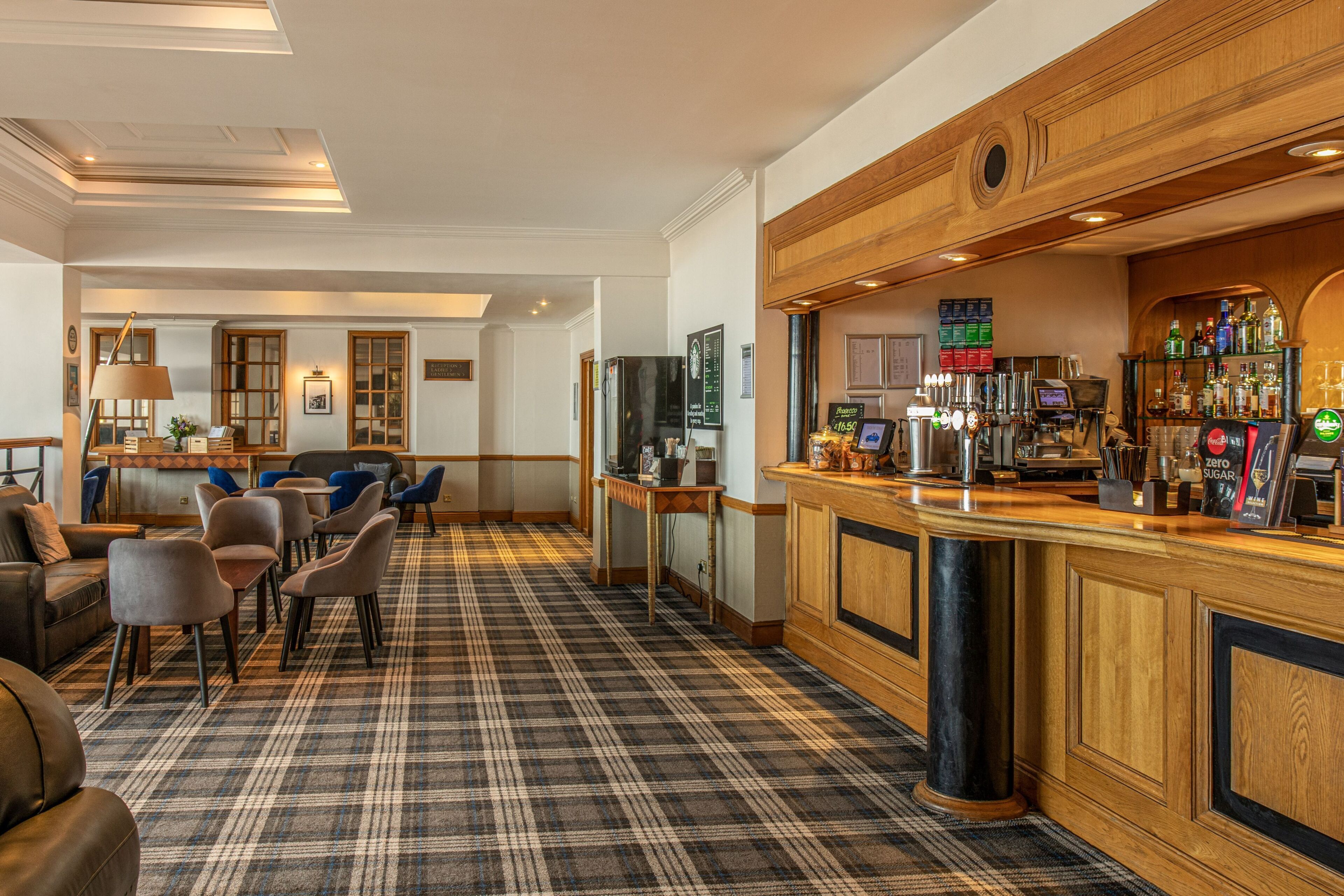 A bar area with a wooden counter, seating, and a check-in desk.