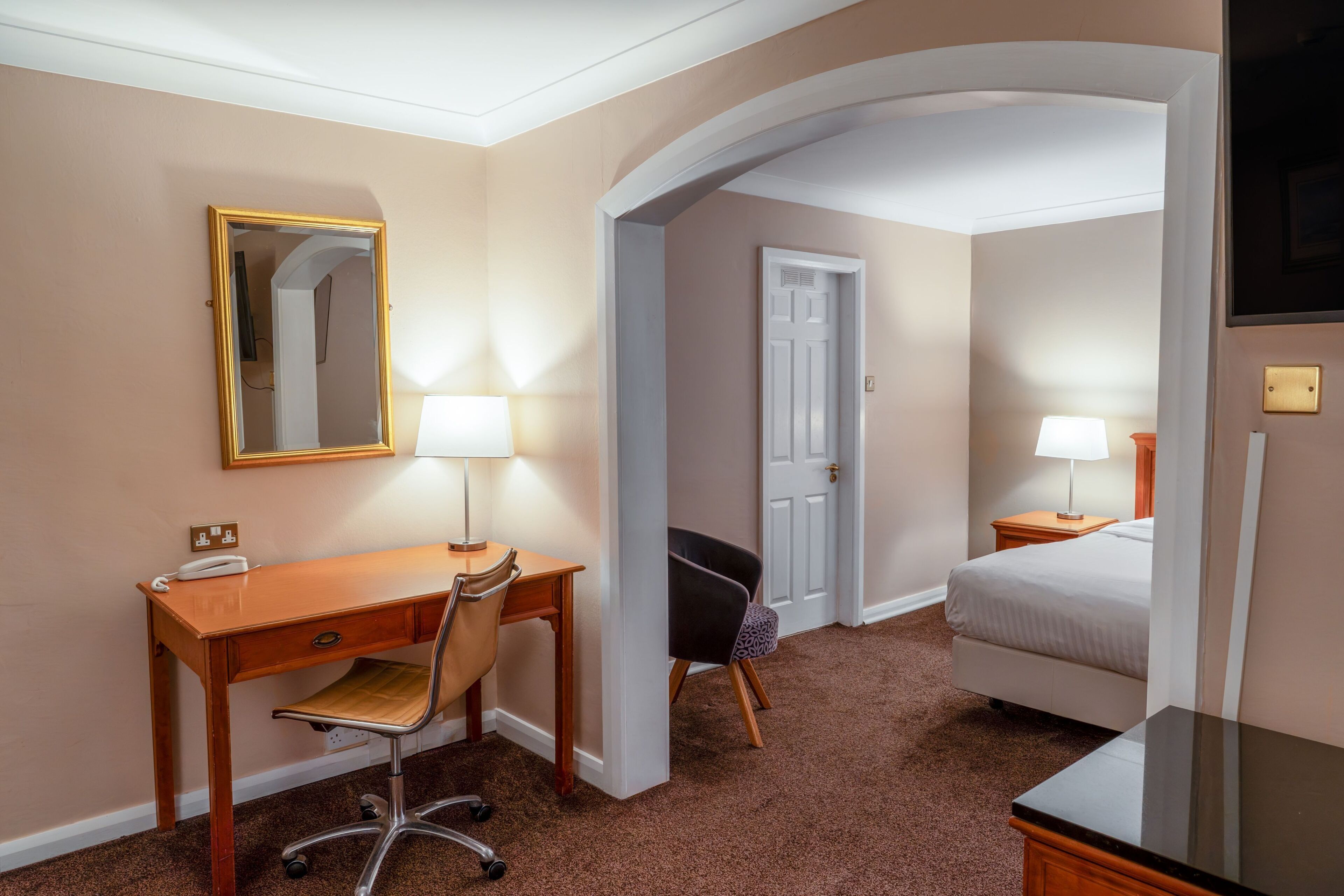 Ein Hotelzimmer mit Schreibtisch, Stuhl, Bett und zwei Nachttischlampen.