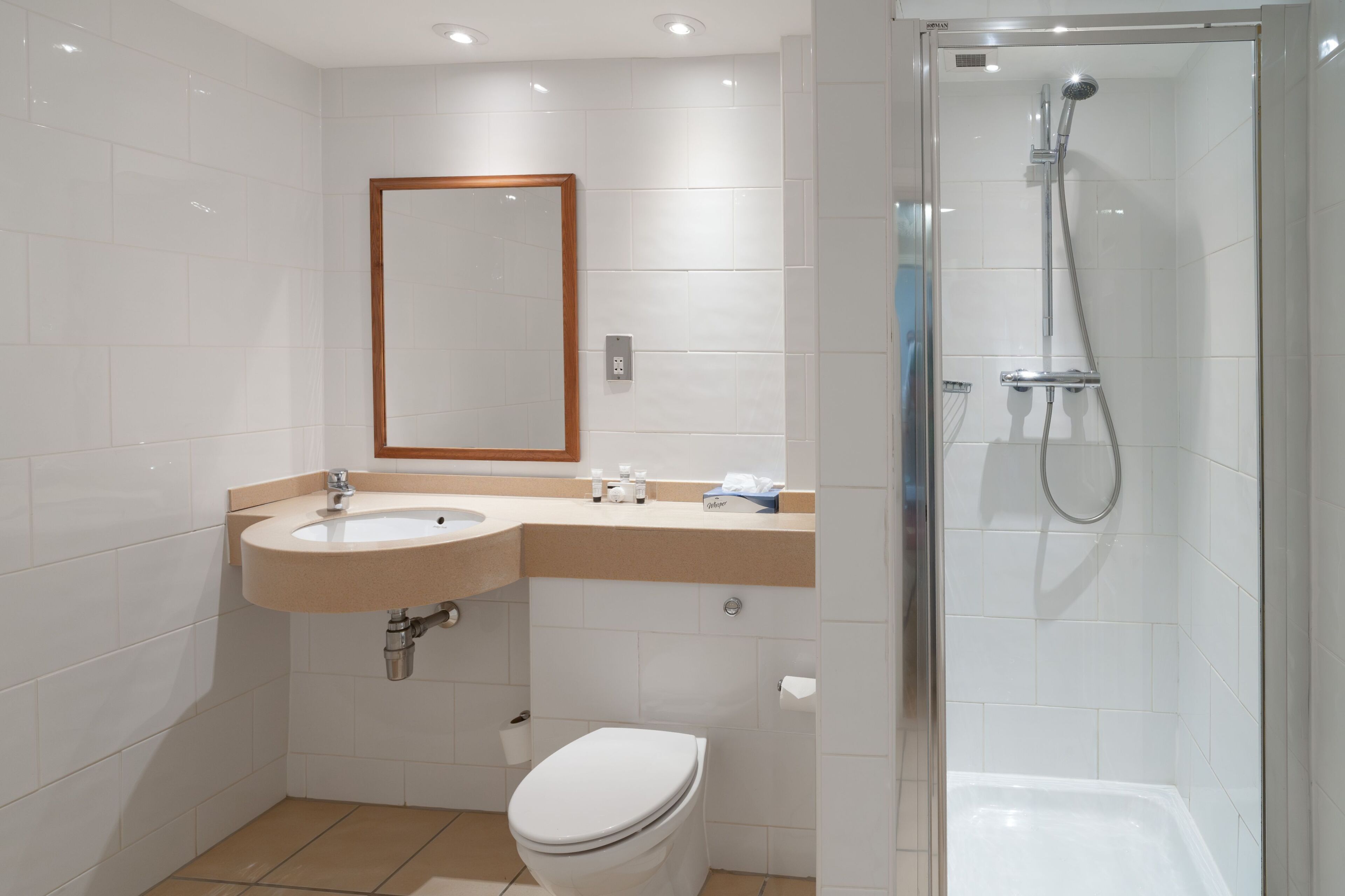 Un baño moderno con lavamanos, inodoro y ducha con mampara de vidrio.