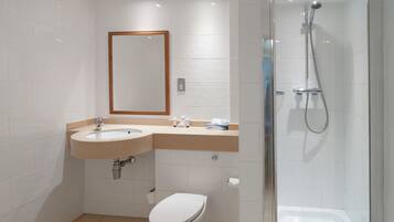 Un baño moderno con lavamanos, inodoro y ducha con mampara de vidrio.