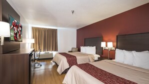 Quarto de hotel com duas camas, uma mesa de trabalho, televisão e janela com cortinas.