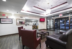 A hotel lobby with a reception desk, seating area, and an exit sign.