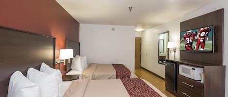 Habitación de hotel con dos camas, televisión, microondas y un refrigerador pequeño.