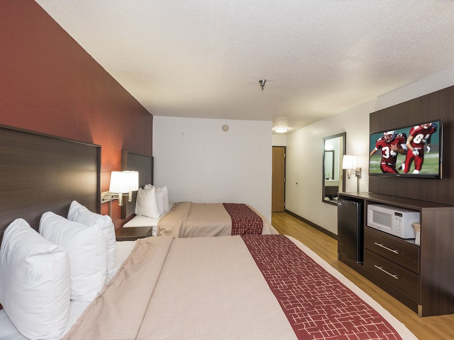 A hotel room with two beds, a television, a microwave, and a small refrigerator.