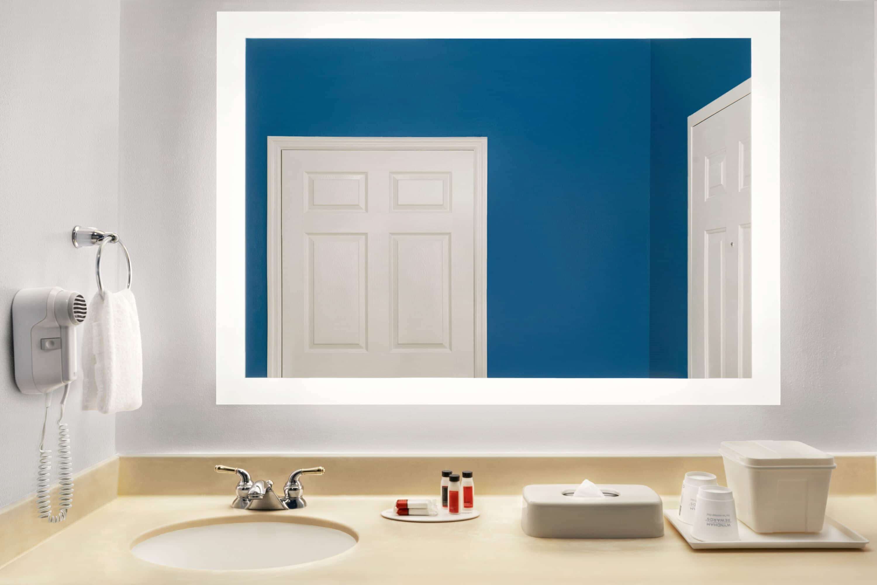 Een badkamer met een wit wastafelmeubel, een spiegel en een blauwe wand.