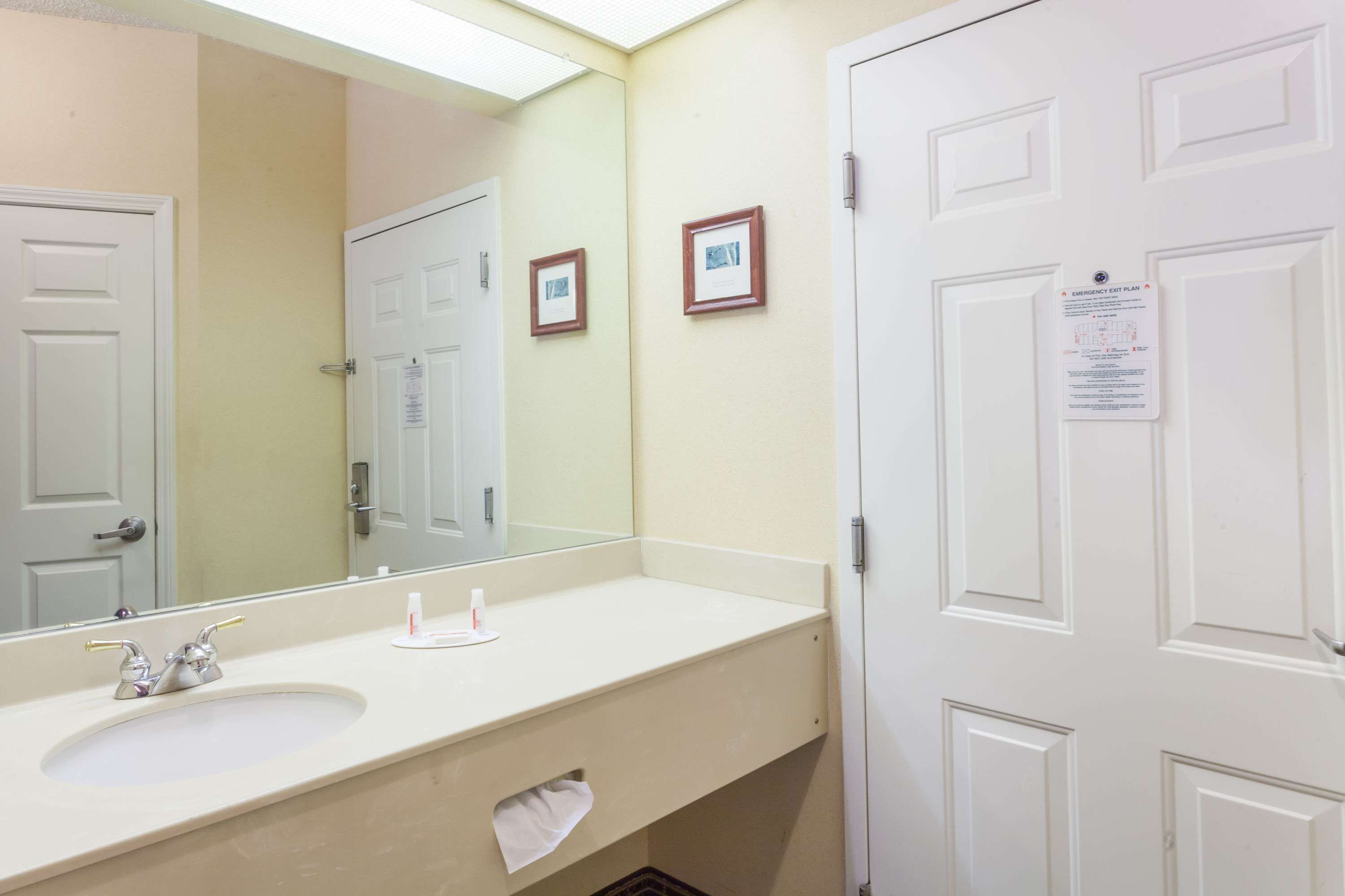 A bathroom with a sink, mirror, and two framed pictures on the wall.