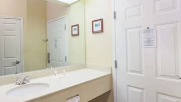 A bathroom with a sink, mirror, and two framed pictures on the wall.