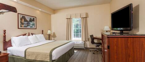 A hotel room with a bed, a desk with a television, a chair, a window with curtains, and a painting on the wall.